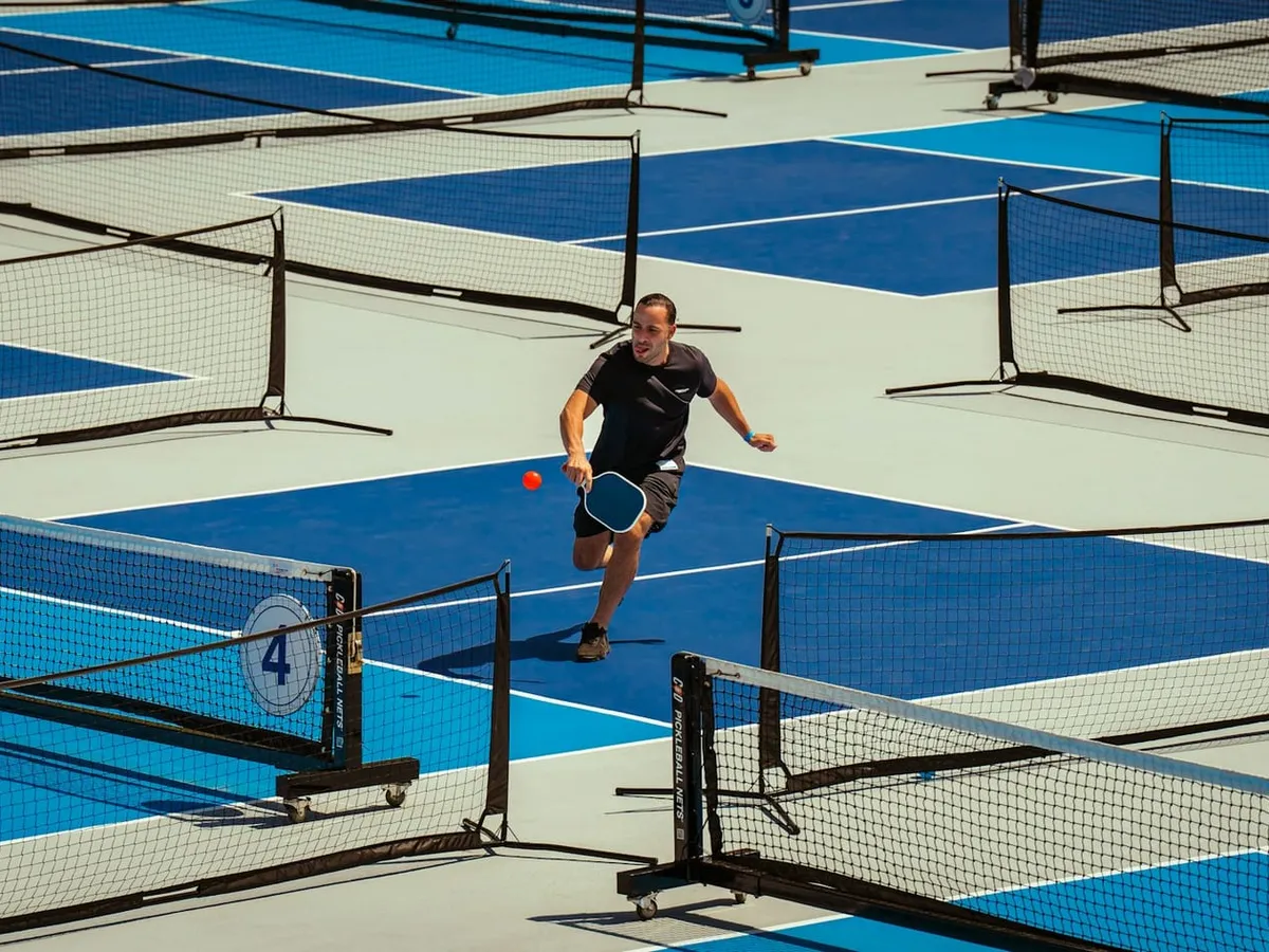 A player lunging to return a pickleball on an outdoor court
